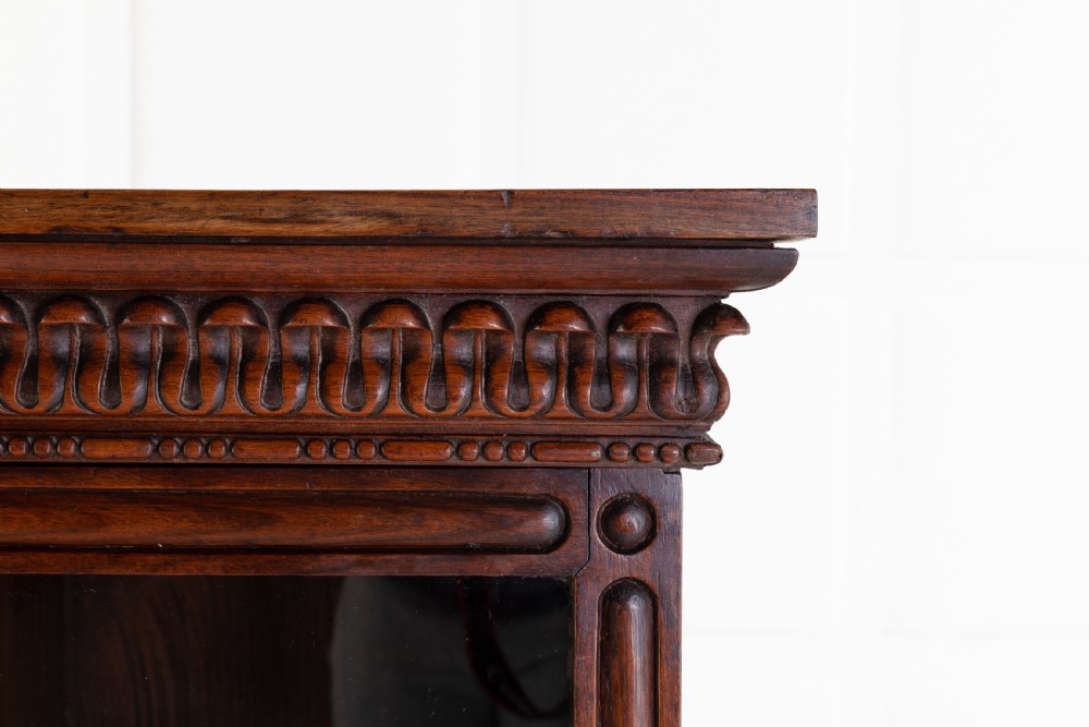 A nineteenth-century Anglo-Indian breakfront bookcase made of dark padouk wood with four glazed doors and carved upper mouldings. View II