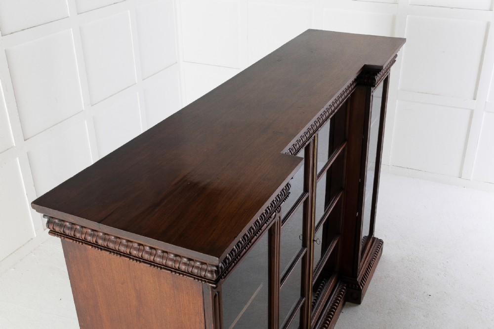 A nineteenth-century Anglo-Indian breakfront bookcase made of dark padouk wood with four glazed doors and carved upper mouldings. View VI