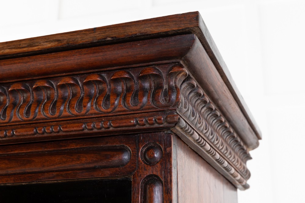A nineteenth-century Anglo-Indian breakfront bookcase made of dark padouk wood with four glazed doors and carved upper mouldings. View VIII