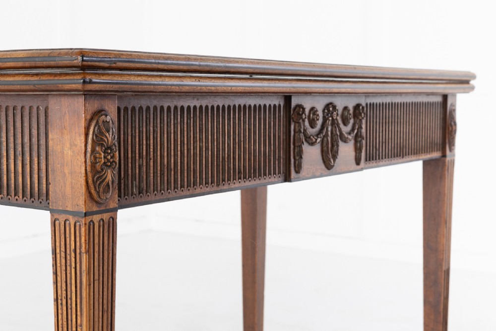 An 18th-century George III mahogany tea table featuring fluted tapering square legs, a reeded frieze with central carved floral swags, and a fold-over top. View III