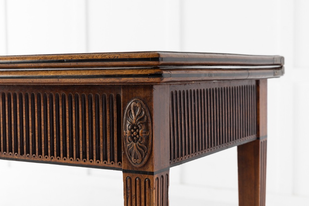 An 18th-century George III mahogany tea table featuring fluted tapering square legs, a reeded frieze with central carved floral swags, and a fold-over top. View V