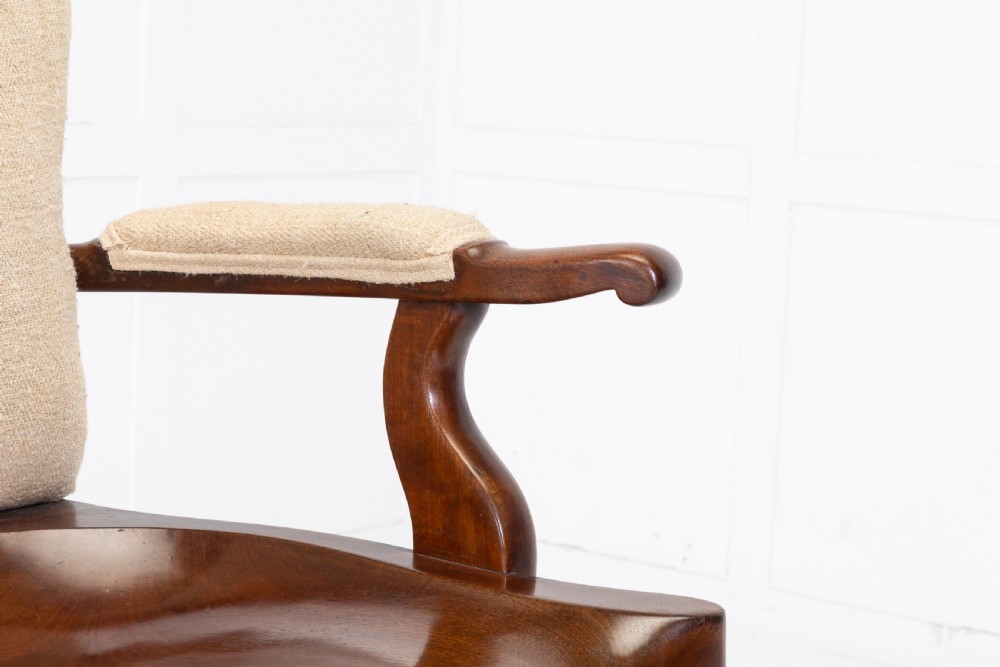 A 19th-century mahogany armchair featuring turned legs on brass castors, a contoured wooden saddle seat, padded armrests, and a beige linen upholstered backrest with central red stripes. View III