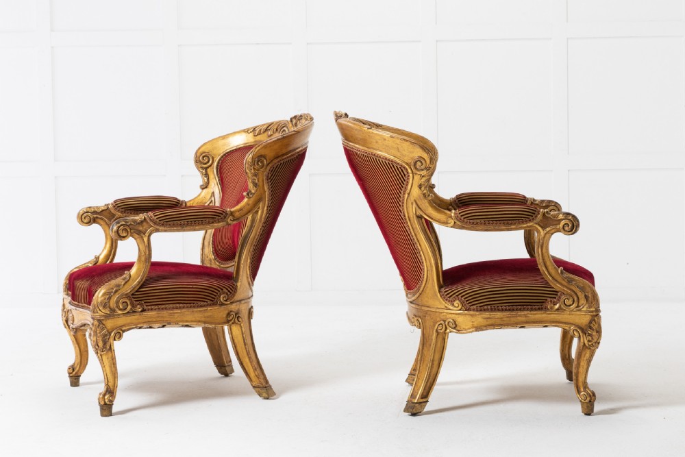 A pair of 18th-century Italian giltwood armchairs with carved scroll motifs and red and gold striped fabric upholstery. View II