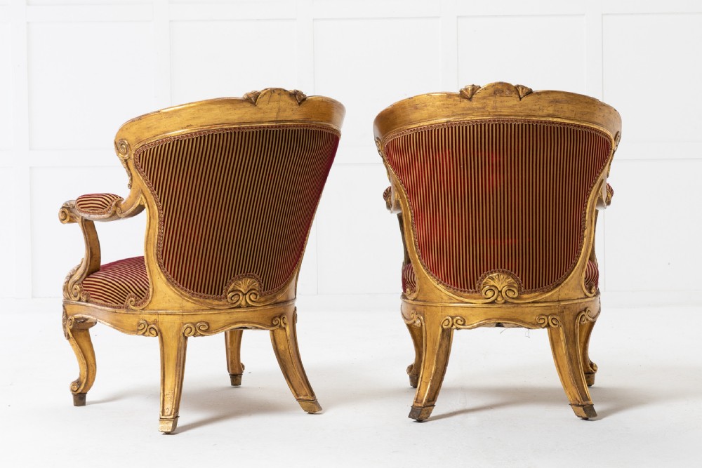 A pair of 18th-century Italian giltwood armchairs with carved scroll motifs and red and gold striped fabric upholstery. View III