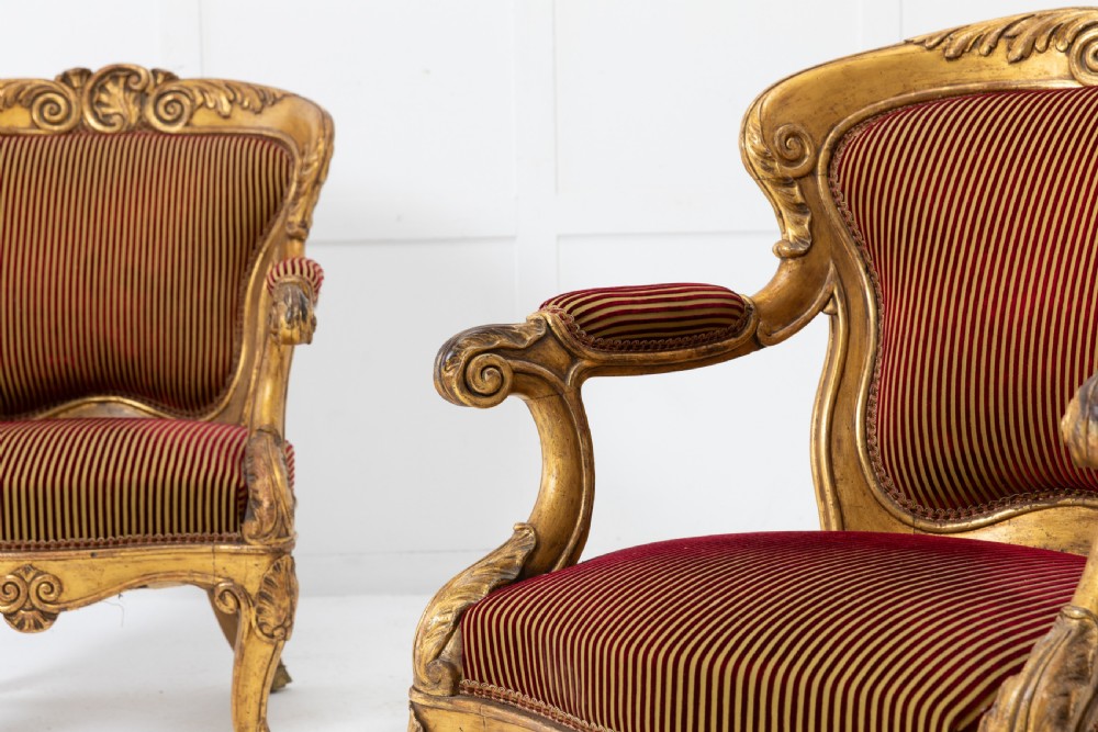 A pair of 18th-century Italian giltwood armchairs with carved scroll motifs and red and gold striped fabric upholstery. View IV