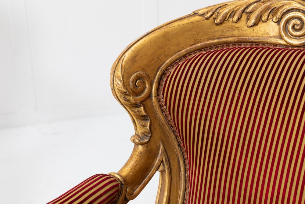 A pair of 18th-century Italian giltwood armchairs with carved scroll motifs and red and gold striped fabric upholstery. View VI