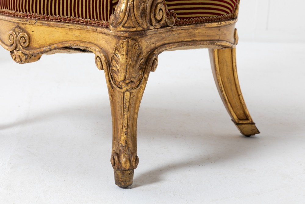 A pair of 18th-century Italian giltwood armchairs with carved scroll motifs and red and gold striped fabric upholstery. View VII