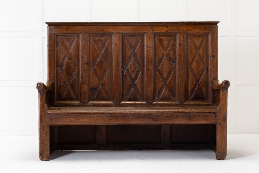 An 18th-century Spanish pine high-backed settle bench featuring carved diamond panels and curved armrests. View II