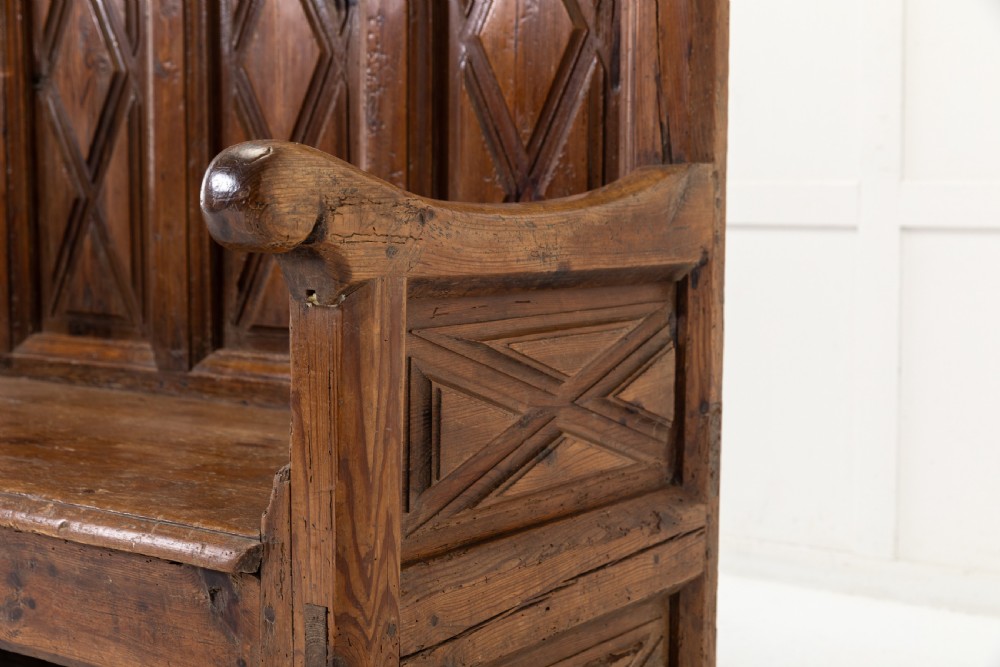 An 18th-century Spanish pine high-backed settle bench featuring carved diamond panels and curved armrests. View III
