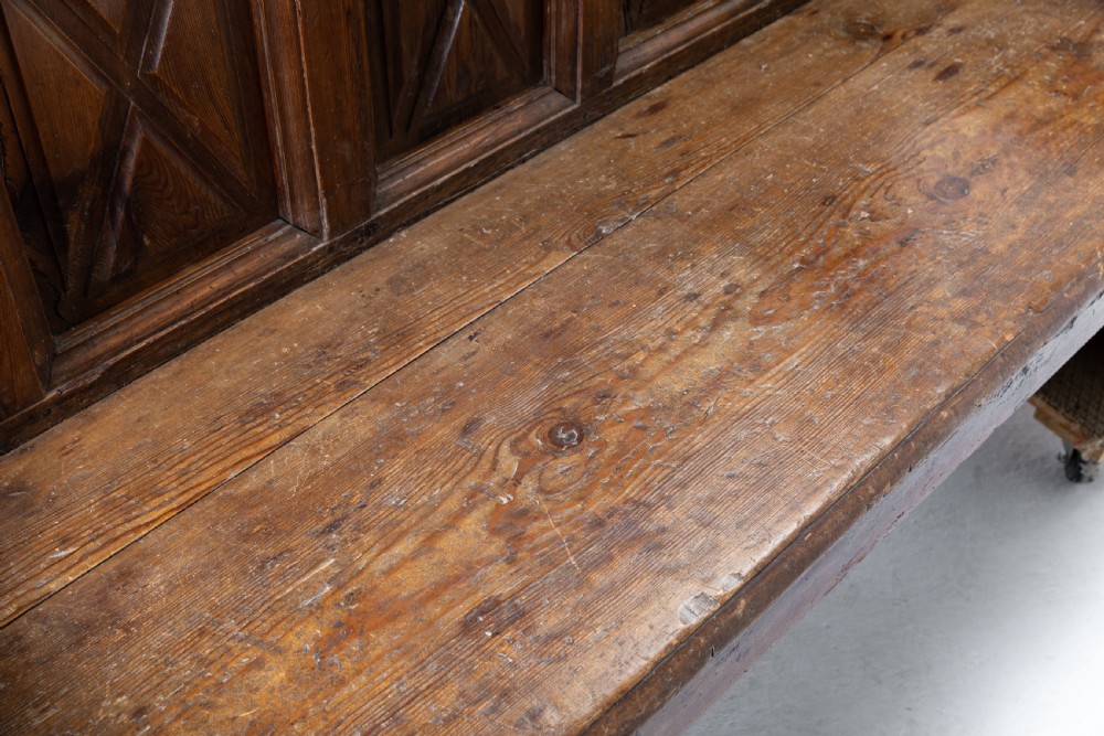 An 18th-century Spanish pine high-backed settle bench featuring carved diamond panels and curved armrests. View V