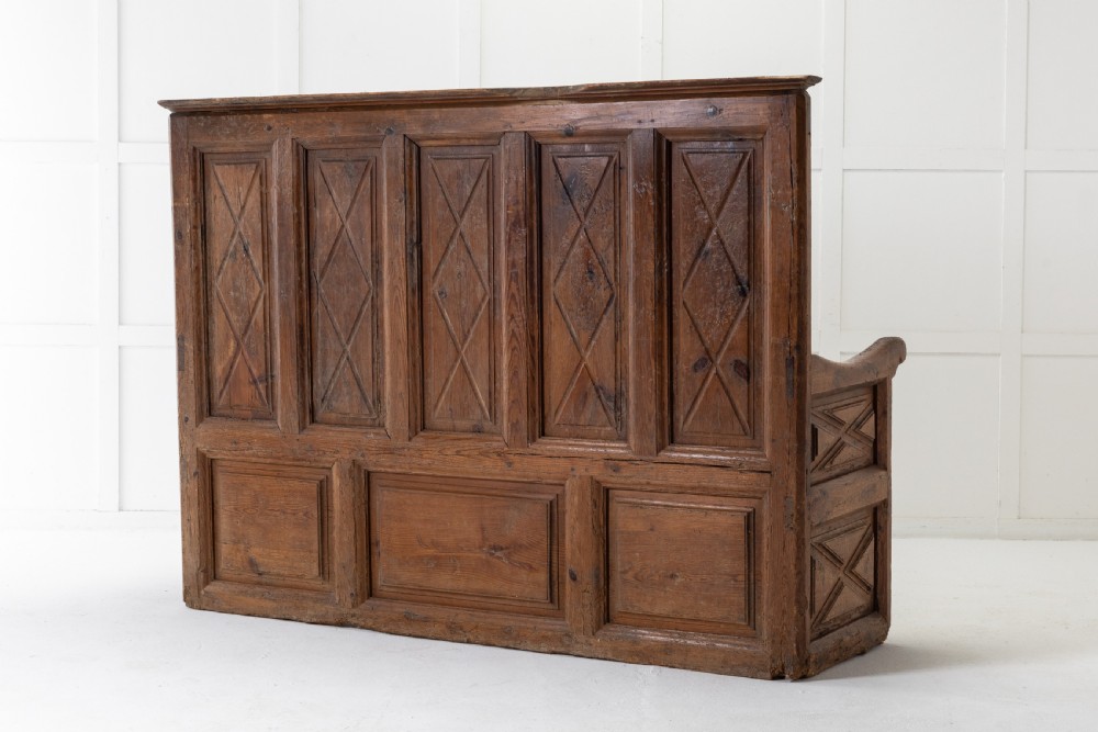 An 18th-century Spanish pine high-backed settle bench featuring carved diamond panels and curved armrests. View VI