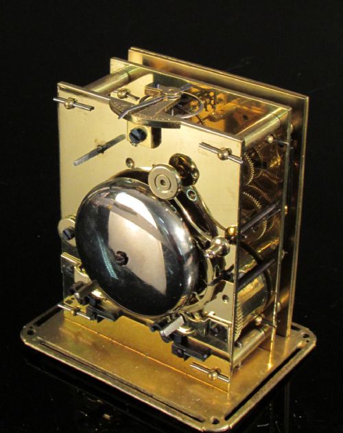fig 1. An engraved gilt brass antique French carriage clock featuring glass side panels, an overhead folding handle, and a white enamel dial with blue Roman numerals.