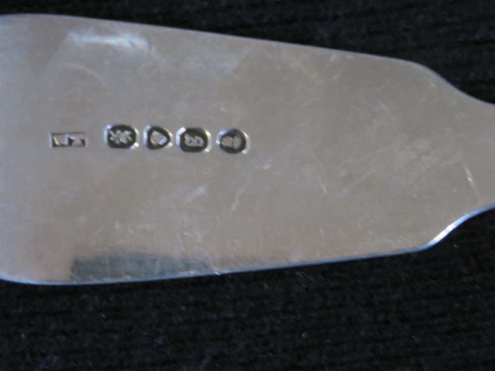 A George III sterling silver basting spoon featuring a plain handle stamped with British hallmarks and a deep oval bowl. View IV