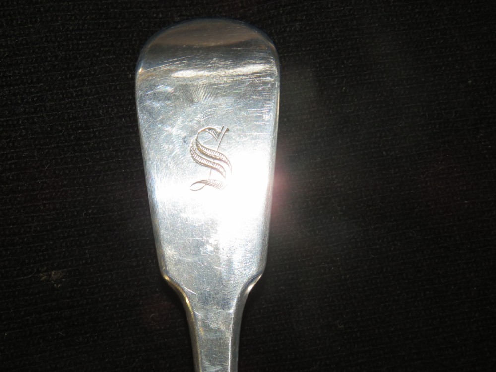 A George III sterling silver basting spoon featuring a plain handle stamped with British hallmarks and a deep oval bowl. View V