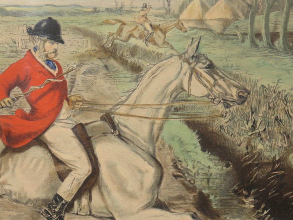 A framed Victorian sporting print depicting equestrian riders and foxhounds in a rural landscape with a windmill in the background, set within a cream mount and black wooden frame. View V