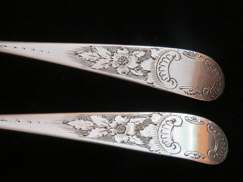 A pair of Georgian sterling silver berry spoons featuring repousse fruit motifs on shaped bowls and detailed engraving along the handles. View III