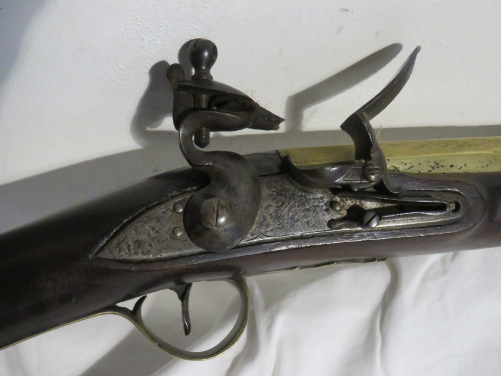 An antique flintlock blunderbuss featuring a flared brass barrel, dark wood stock, iron lock mechanism, and brass trigger guard. View II