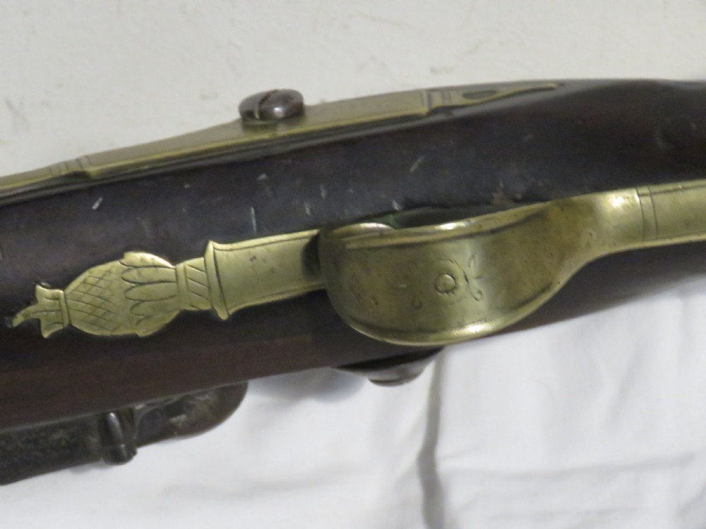 An antique flintlock blunderbuss featuring a flared brass barrel, dark wood stock, iron lock mechanism, and brass trigger guard. View V
