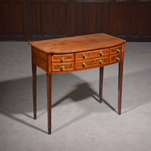 fig 1. An antique Sheraton style mahogany bowfront side table with stringing inlay, brass handles, and square tapered legs.