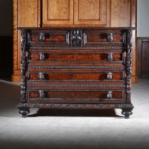 fig 2. A dark carved walnut Italian Renaissance style chest of drawers featuring small carved figural pilasters and turned bun feet.