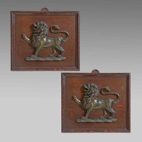 fig 1. A cast bronze lion passant heraldic relief mounted on a rectangular dark red-brown painted wooden plaque.