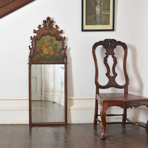 fig 1. An 18th-century Dutch walnut pier mirror featuring a carved cresting, an upper panel with a floral still-life oil painting, and a tall rectangular glass plate.