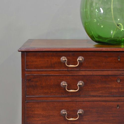 fig 1. A Georgian dark mahogany straight-front chest of drawers featuring five graduated drawers with brass swan-neck handles and bracket feet.