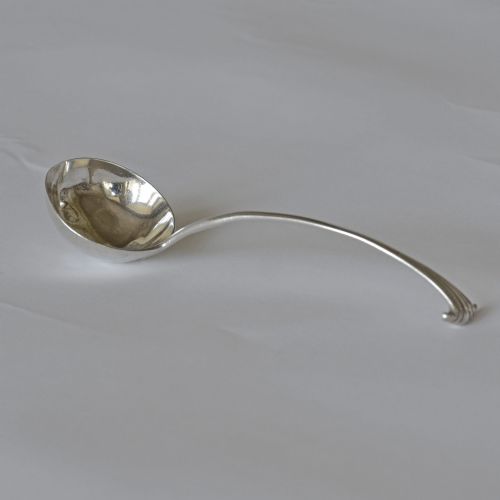 fig 1. An 18th-century Georgian sterling silver ladle featuring a deep circular bowl and a curved handle with a scrolled terminal.