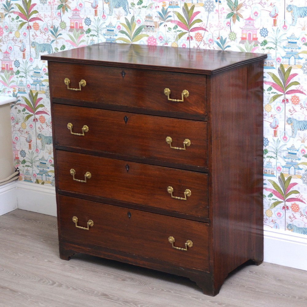 An Anglo-Indian padauk wood chest of drawers featuring four graduated drawers with brass bail handles and bracket feet.