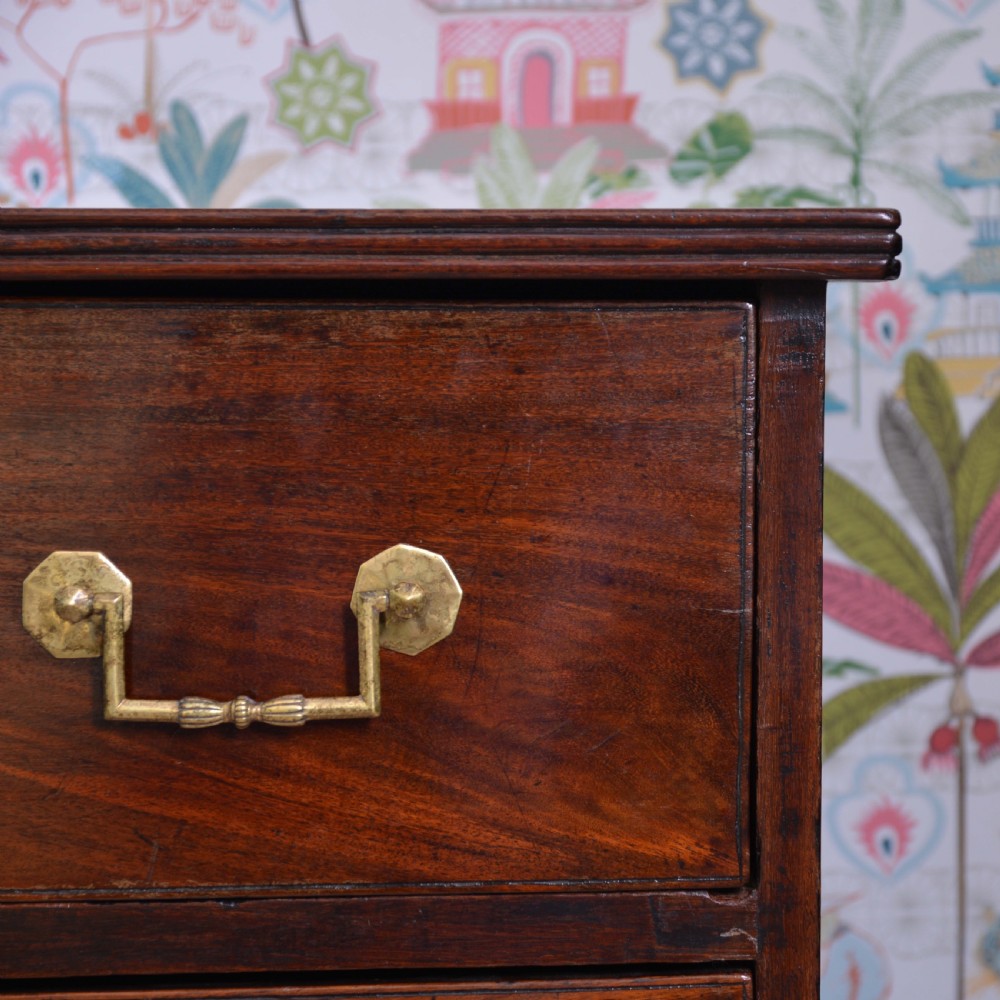 An Anglo-Indian padauk wood chest of drawers featuring four graduated drawers with brass bail handles and bracket feet. View III