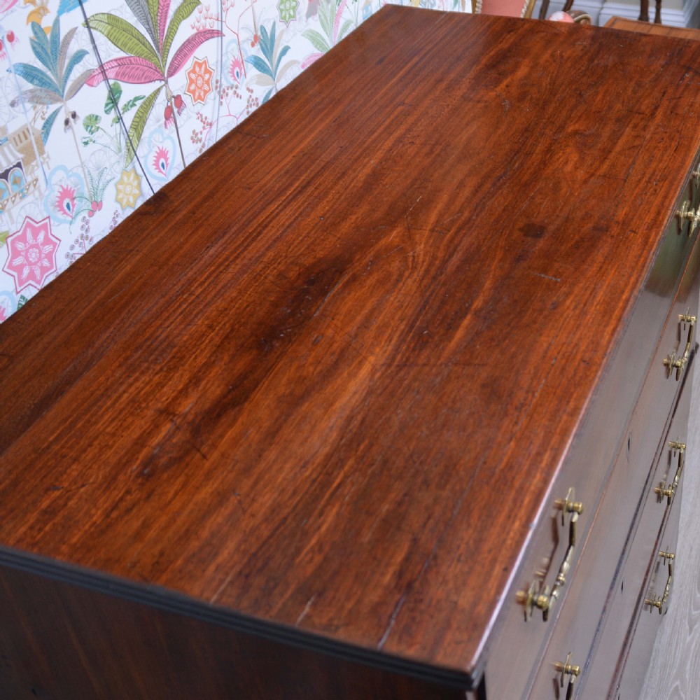 An Anglo-Indian padauk wood chest of drawers featuring four graduated drawers with brass bail handles and bracket feet. View VI