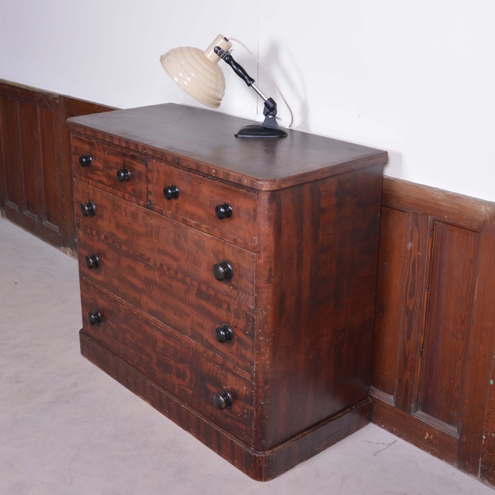 A 19th-century pine chest of drawers featuring a hand-painted scumbled faux-grain finish, two short over three long drawers, dark turned wooden knobs, and a solid plinth base.