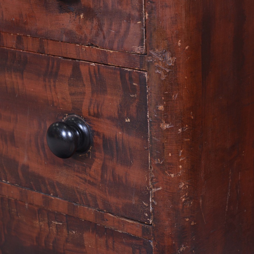 A 19th-century pine chest of drawers featuring a hand-painted scumbled faux-grain finish, two short over three long drawers, dark turned wooden knobs, and a solid plinth base. View II