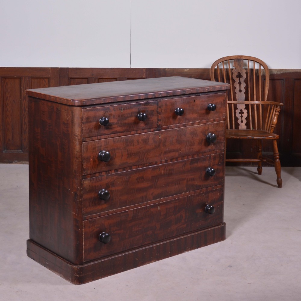 A 19th-century pine chest of drawers featuring a hand-painted scumbled faux-grain finish, two short over three long drawers, dark turned wooden knobs, and a solid plinth base. View VI