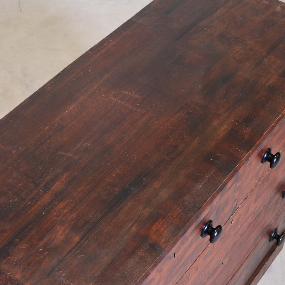 A 19th-century pine chest of drawers featuring a hand-painted scumbled faux-grain finish, two short over three long drawers, dark turned wooden knobs, and a solid plinth base. View VII