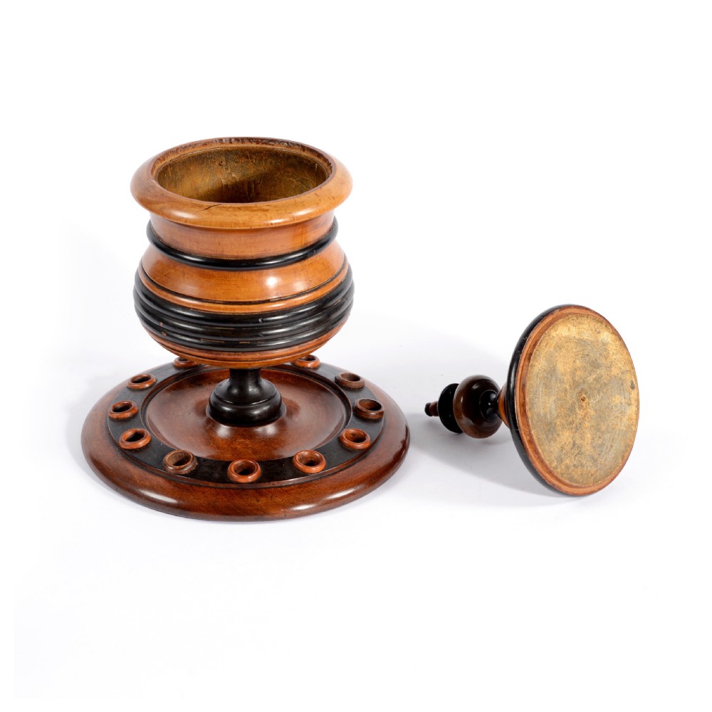 A turned fruitwood tobacco box featuring ebonised ring bands, a tiered lid with a turned finial, and a circular base with pipe holders. View II
