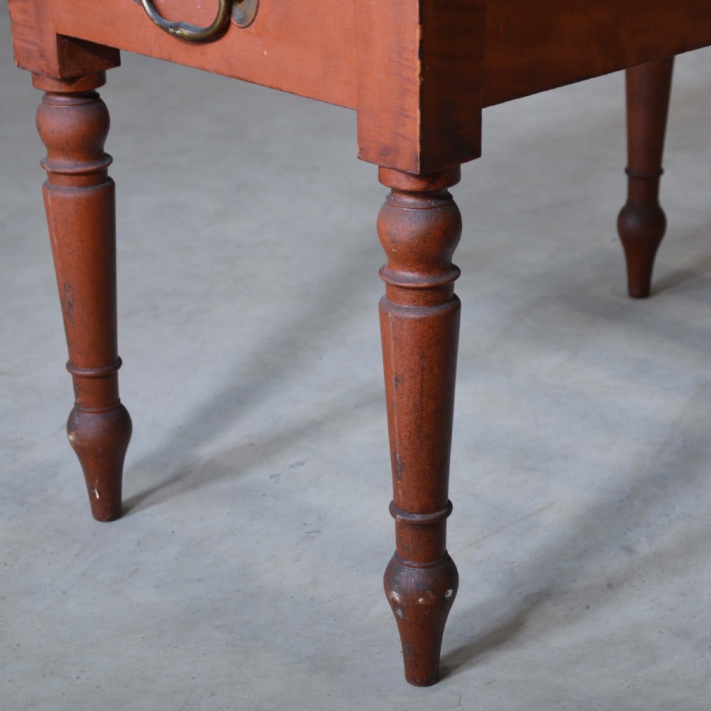 A low rectangular pine luggage stand painted in terracotta red with a slatted top surface, side handles, and four turned legs. View V