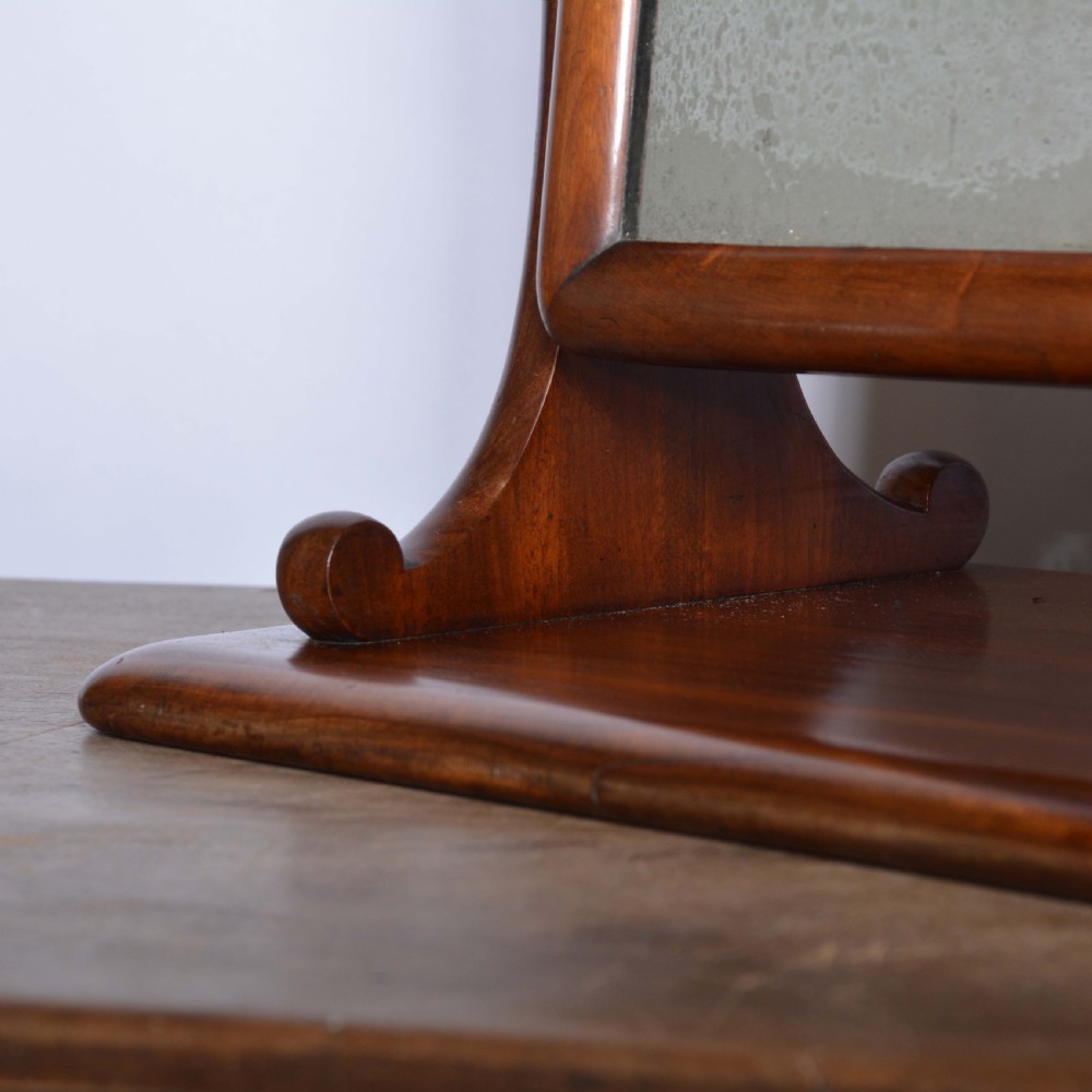 An antique mahogany dressing table mirror featuring a rectangular swivelling frame set between curved upright supports on a solid plinth base. View IV