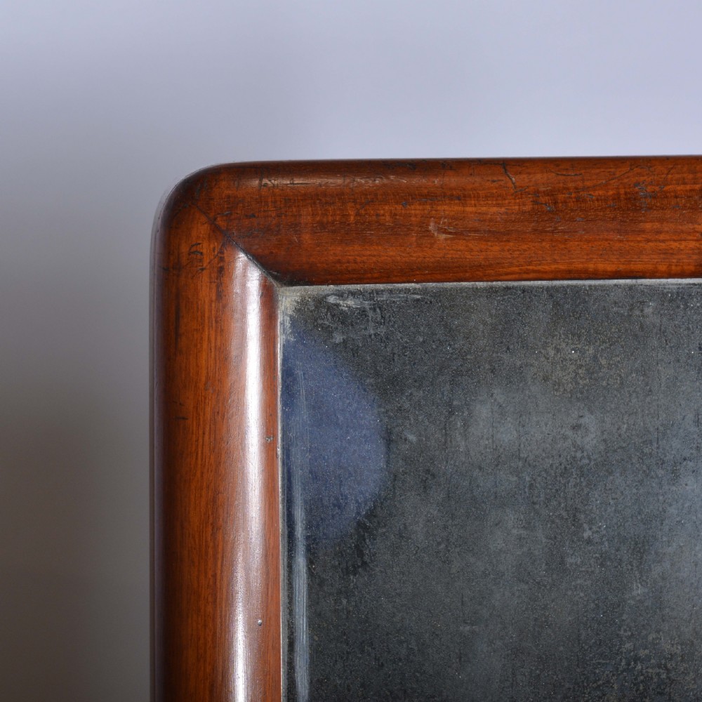 An antique mahogany dressing table mirror featuring a rectangular swivelling frame set between curved upright supports on a solid plinth base. View V