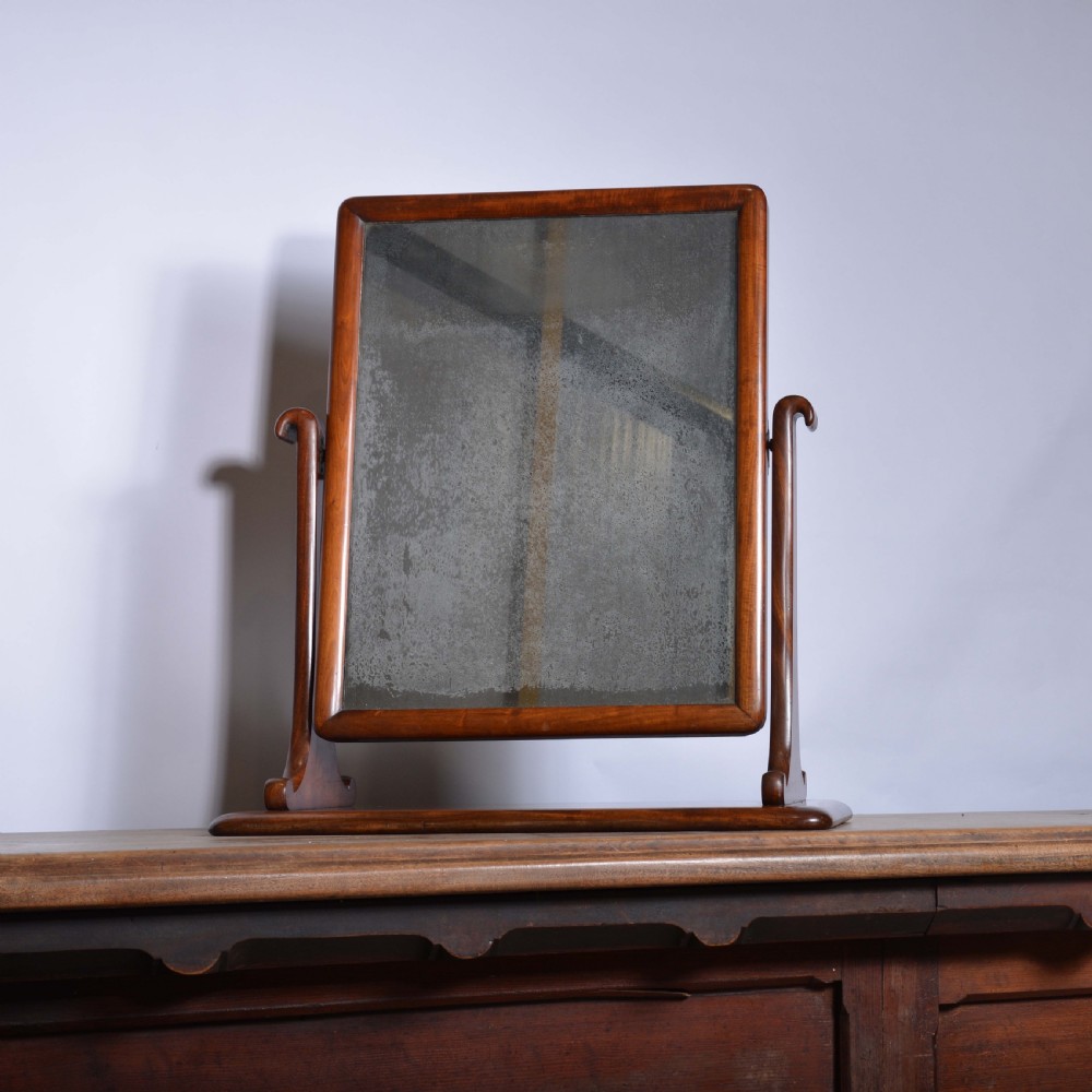 An antique mahogany dressing table mirror featuring a rectangular swivelling frame set between curved upright supports on a solid plinth base. View VI