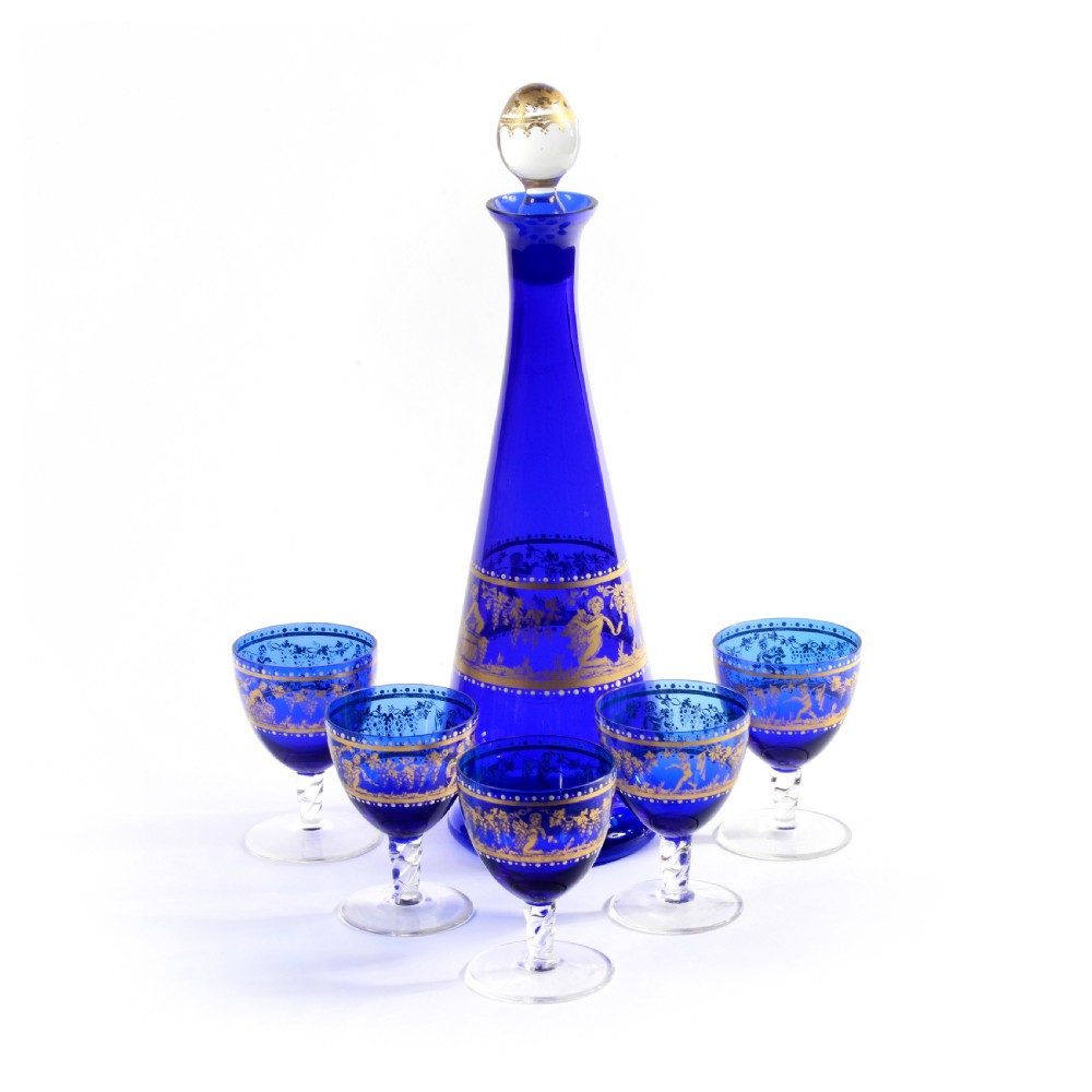 A 19th-century Venetian cobalt blue glass decanter bottle with stopper and matching stemmed glasses featuring gilded classical motifs and clear twisted glass stems. View II