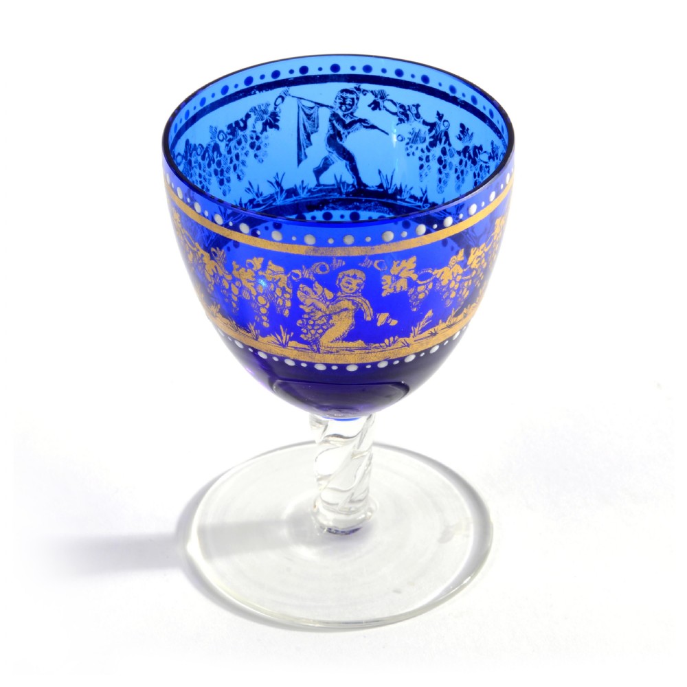 A 19th-century Venetian cobalt blue glass decanter bottle with stopper and matching stemmed glasses featuring gilded classical motifs and clear twisted glass stems. View VII