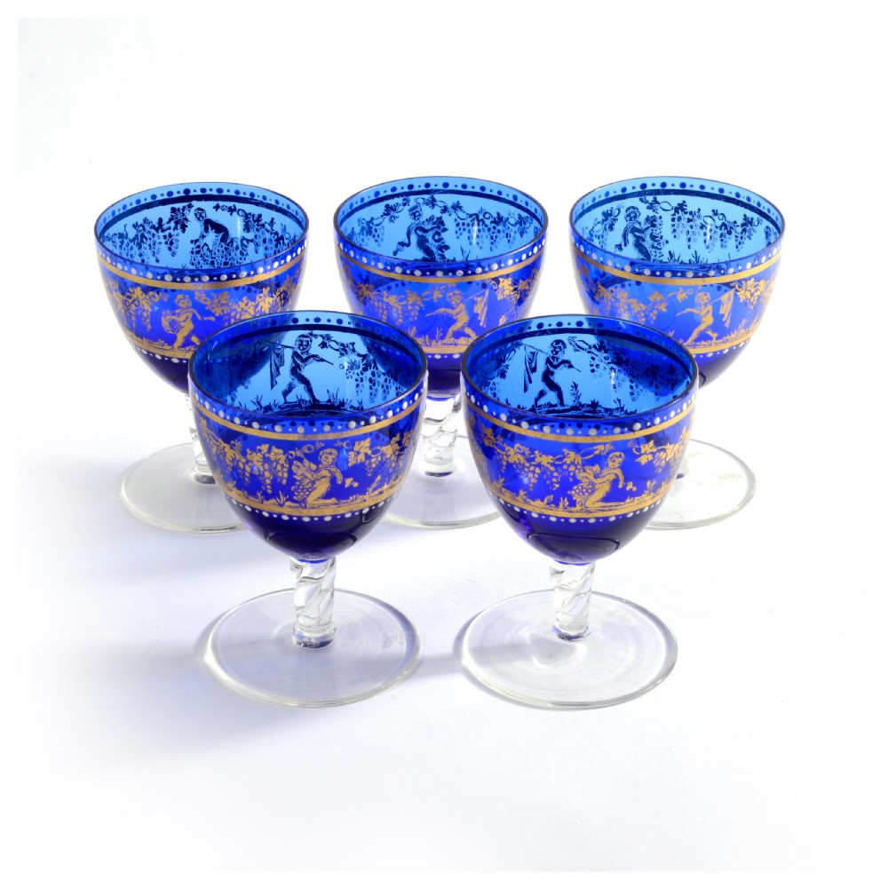 A 19th-century Venetian cobalt blue glass decanter bottle with stopper and matching stemmed glasses featuring gilded classical motifs and clear twisted glass stems. View VIII