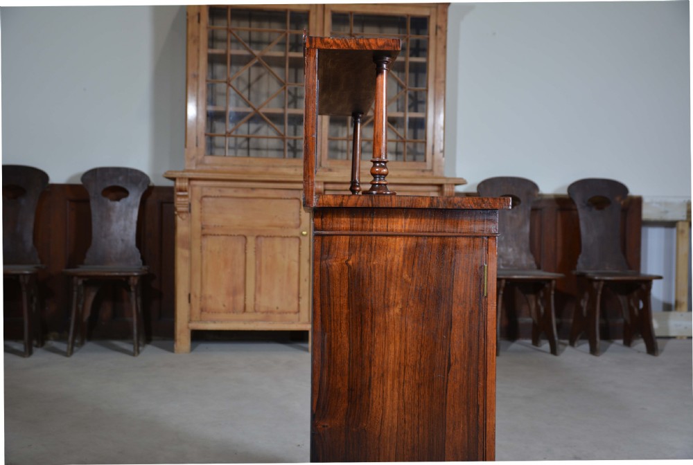 A Regency dwarf rosewood chiffonier featuring two red fabric-lined panel doors, a raised upper shelf supported by turned columns, and bun feet. View III