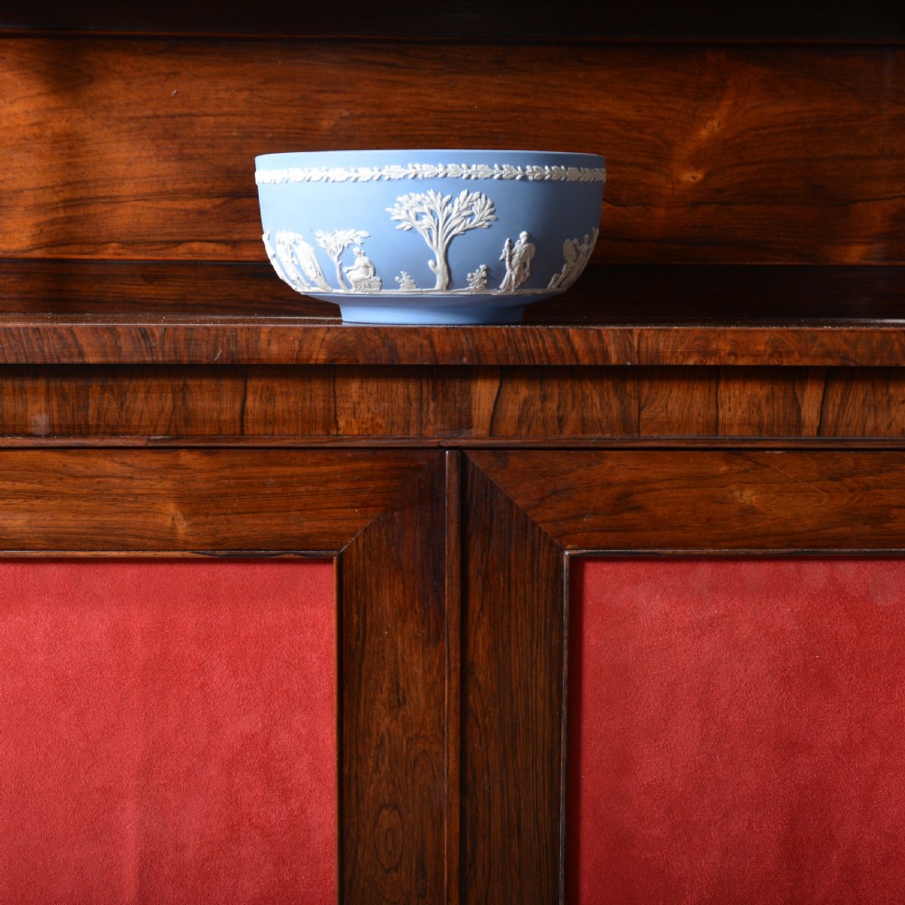 A Regency dwarf rosewood chiffonier featuring two red fabric-lined panel doors, a raised upper shelf supported by turned columns, and bun feet. View VI