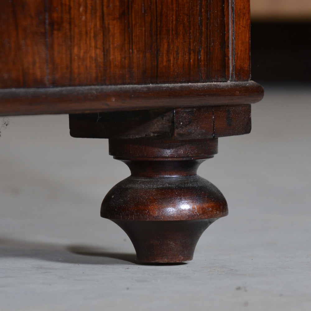 A Regency dwarf rosewood chiffonier featuring two red fabric-lined panel doors, a raised upper shelf supported by turned columns, and bun feet. View X