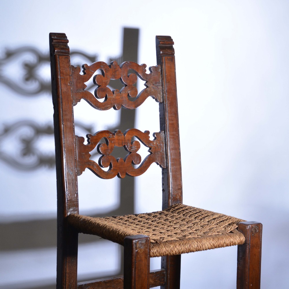 A small Italian country walnut side chair featuring two scroll-carved back splats, a woven rush seat, and sturdy square legs. View II
