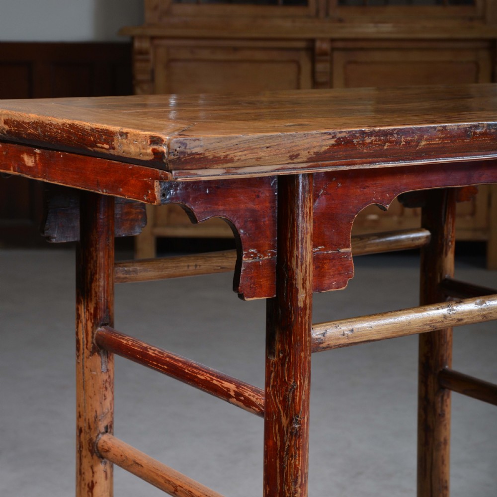 An antique Chinese rectangular elm half table featuring distressed red lacquer, carved apron spandrels, and round legs with stretchers. View III