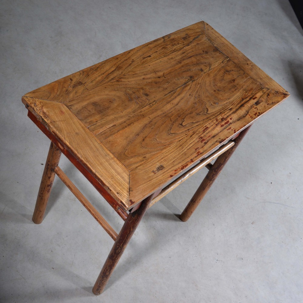 An antique Chinese rectangular elm half table featuring distressed red lacquer, carved apron spandrels, and round legs with stretchers. View VI