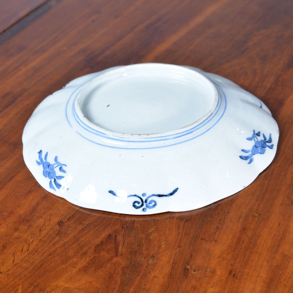 A 19th-century Japanese Imari porcelain circular dish featuring a scalloped rim, central blue medallion, and panelled floral decoration in iron red, cobalt blue, and green enamels. View III
